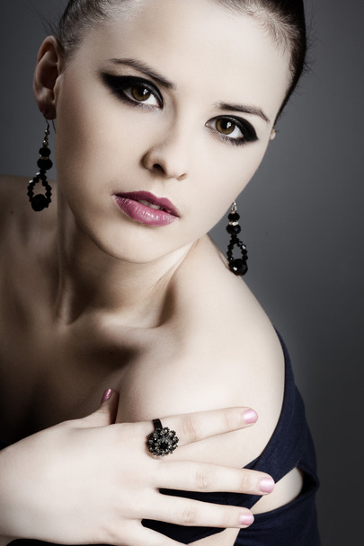 Beautiful girl with perfect skin in black dress with jewelry on a dark back - Zdjęcie, obraz