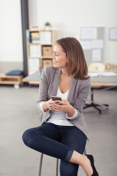 Smiling Office Woman on a Stool Holding Phone - Photo, Image