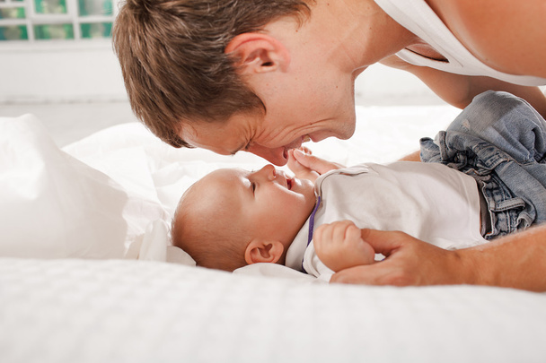 young father with his nine months old son on the bed at home - Foto, Bild