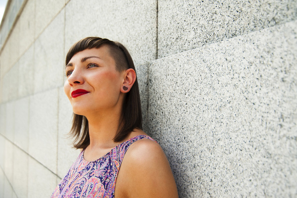 Jovem mulher moderna em pé contra a parede sorrindo. Lábios vermelhos
 - Foto, Imagem