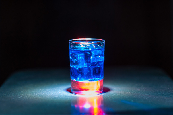 Blauwe alcoholische cocktail is in glas, op de balk  - Foto, afbeelding