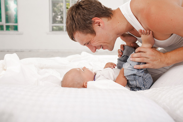 jeune père avec son fils de neuf mois sur le lit à la maison
 - Photo, image
