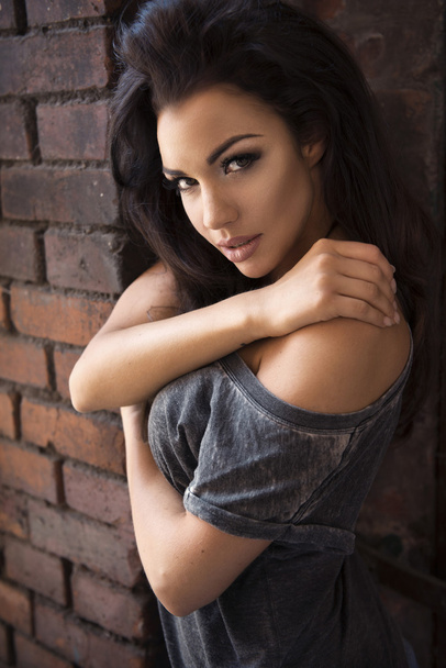 Sensual brunette woman posing on brick wall - Photo, Image