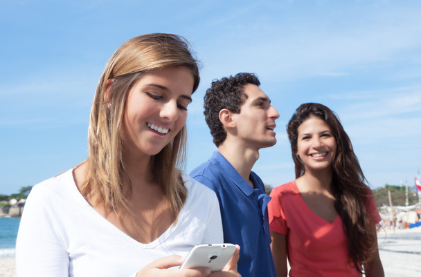 Young woman with friends typing a message on phone - Photo, image