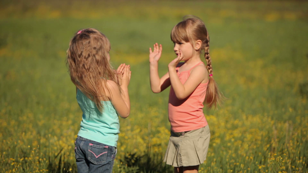 Dos niñas aplauden con las manos en flores
. - Metraje, vídeo