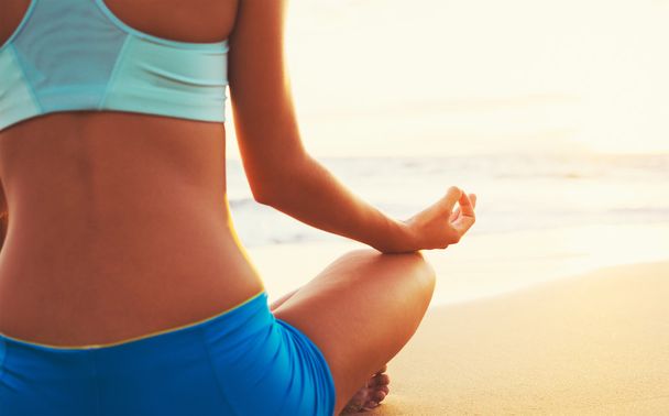 nő gyakorló jóga a strandon naplementekor - Fotó, kép