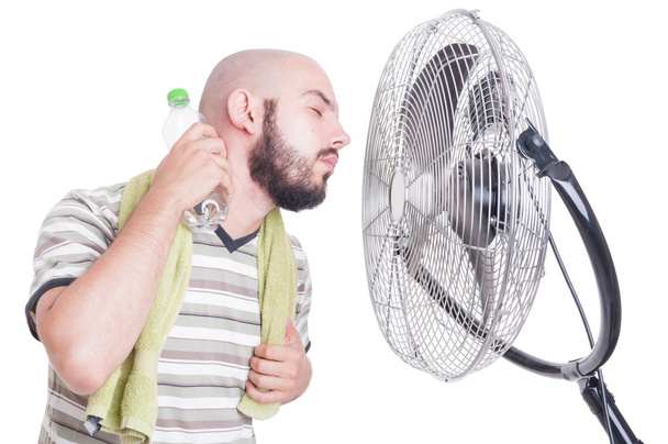 Man zijn hals met koud water fles en fan koeling - Foto, afbeelding
