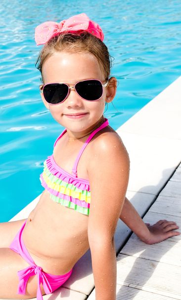 Smiling little girl sitting near swimming pool  - Fotó, kép