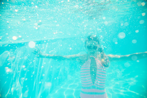 Молода дівчина в сонцезахисних окулярах плаває під водою
 - Фото, зображення