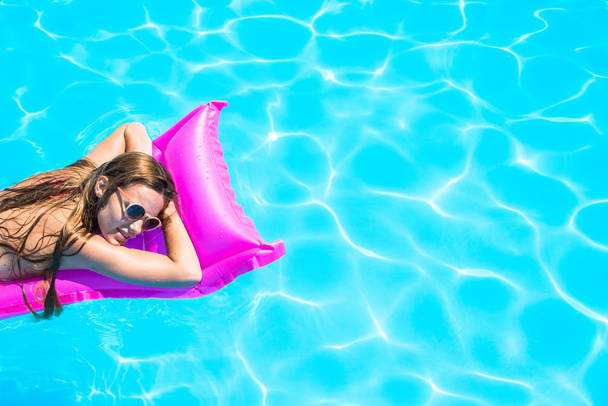 Девушка плавает на надувном матрасе в бассейне
 - Фото, изображение