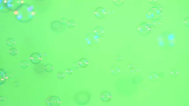 Blue and clear soap bubbles on green, background, slow motion - Footage, Video