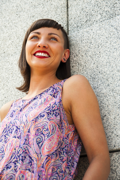 Jonge moderne vrouw permanent tegen de muur glimlacht. Rode lippen een - Foto, afbeelding