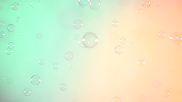 Blue and clear soap bubbles on turquoise and light pink, background, slow motion - Footage, Video