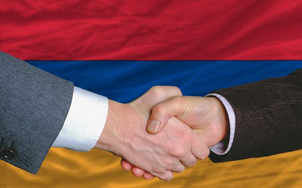 hombres de negocios apretón de manos después de un buen trato frente a la bandera de Armenia
 - Foto, imagen