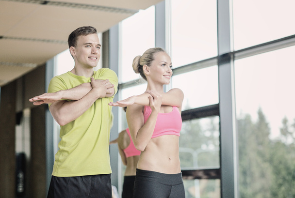 smiling man and woman exercising in gym - Foto, Bild