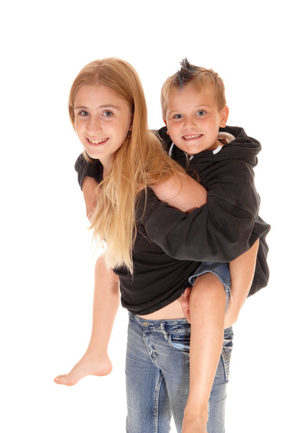 Young pretty girl is piggybacking little brother. - Фото, изображение