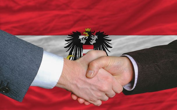 hombres de negocios apretón de manos después de un buen trato frente a la bandera austriaca
 - Foto, Imagen