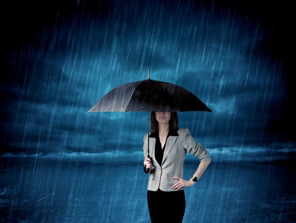 Business woman standing in rain with an umbrella - Foto, imagen