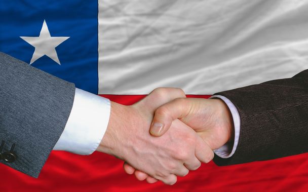 hombres de negocios apretón de manos después de un buen trato frente a la bandera de Chile
 - Foto, Imagen