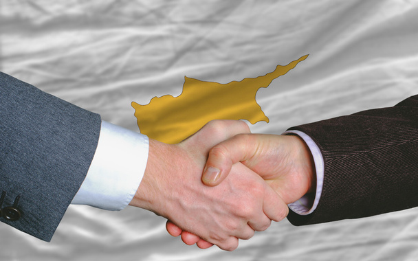 Empresarios apretón de manos después de un buen trato frente a la bandera de Cyprus
 - Foto, imagen