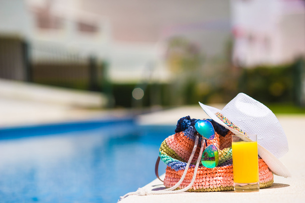 Летний концепт-рюкзак, вкусный апельсиновый сок и белая шляпа у открытого бассейна
 - Фото, изображение