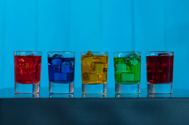 Яркие алкогольные напитки или ягоды коктейль в разных цветах, стаканы барабан на деревянном фоне
 - Фото, изображение