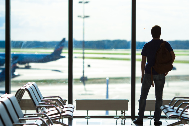 Силуэт человека, ожидающего посадки на рейс в аэропорту
 - Фото, изображение