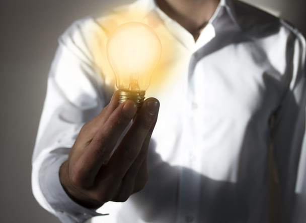 Бизнесмен с освещаемой лампочкой балансирует на руке
  - Фото, изображение