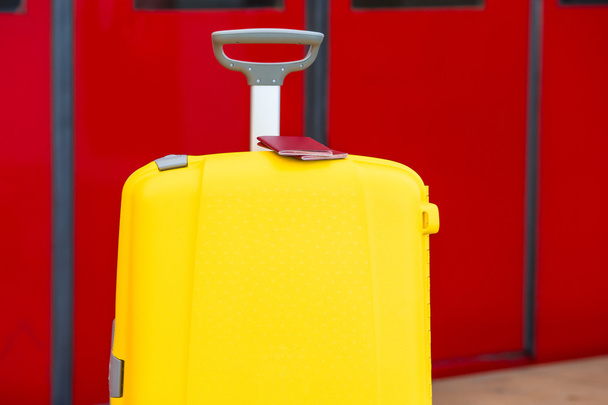 Nahaufnahme roter Pässe auf gelbem Gepäck am Bahnhof - Foto, Bild