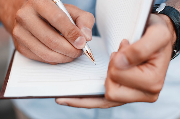 Άνθρωπος συγγραφή σημειώσεων σε ένα σημειωματάριο. Χέρι εκμετάλλευση στυλό - Φωτογραφία, εικόνα