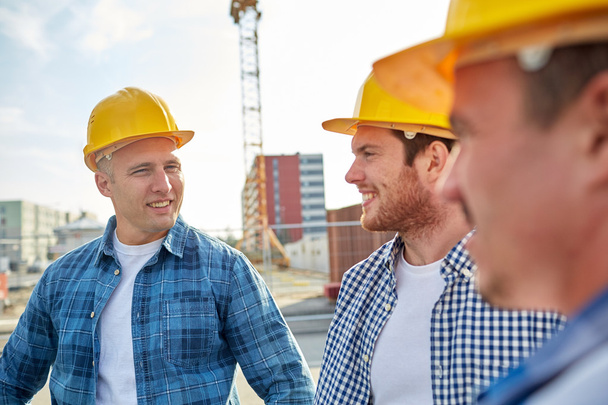 group of smiling builders in hardhats outdoors - Photo, image