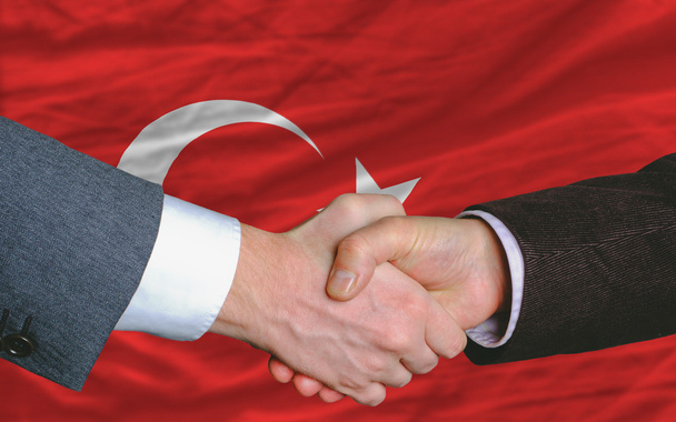 Geschäftsleute geben sich nach gutem Deal vor türkischer Flagge die Hand - Foto, Bild