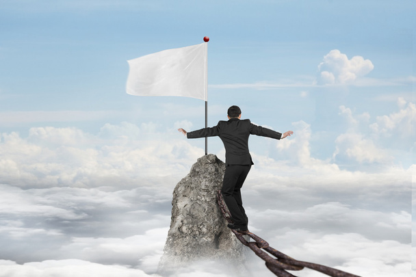 Businessman walking on iron chain toward white flag with cloudsc - Foto, afbeelding