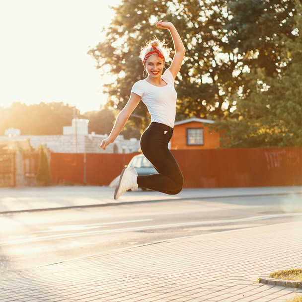 Mooi meisje sprong in de buurt van een weg bij zonsondergang - Foto, afbeelding