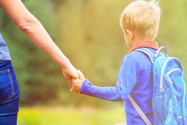 Mother holding hand of little son with backpack outdoors - Photo, Image