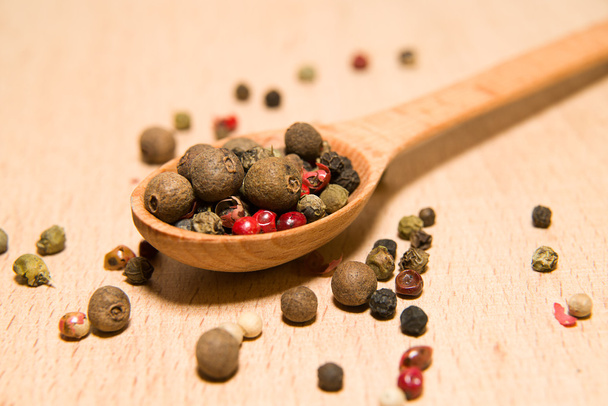 Spoon filled with a mixture of grains of pepper are on a wooden  - Photo, Image