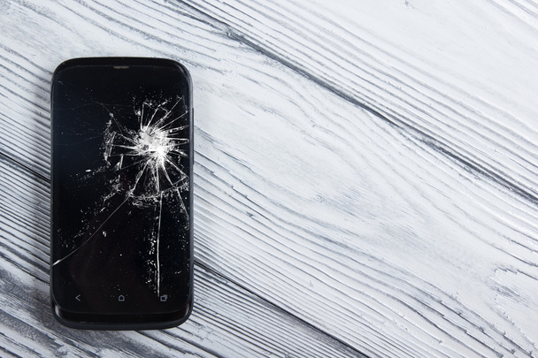 Modern broken mobile phone on white wooden background. Copy space. Top view - Foto, Bild