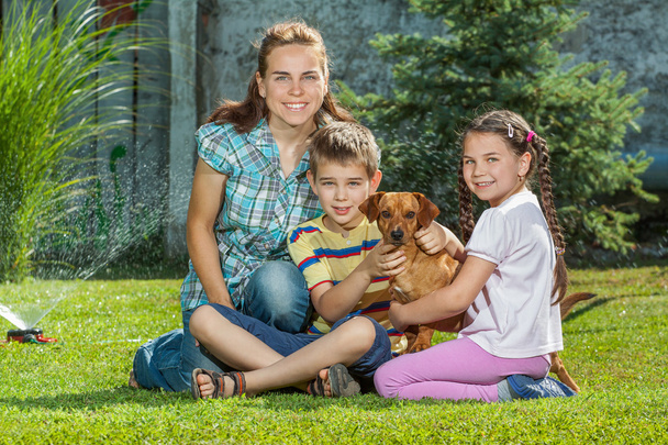 Красивая семья матери, сына и дочери со своей собакой
, - Фото, изображение