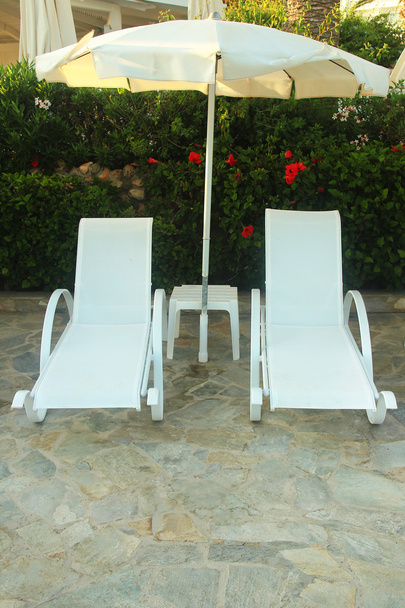 Liegestühle und Sonnenschirm am Pool - Foto, Bild