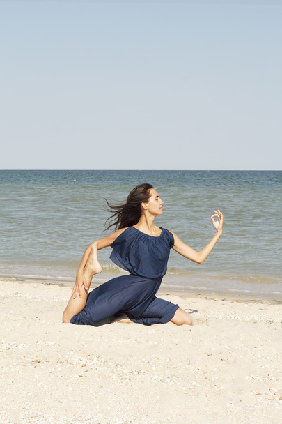 junge schöne Frau macht Yoga am Meer in blauem Kleid - Foto, Bild