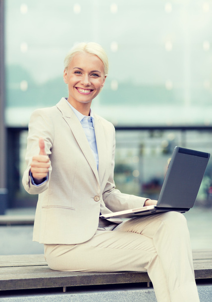 smiling businesswoman working with laptop outdoors - Photo, image