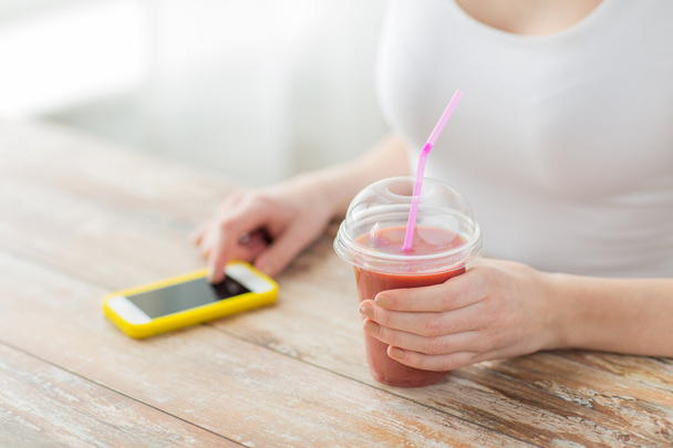 close up of woman with smartphone and smoothie - Fotó, kép