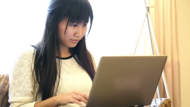 Asiática mujer sentada en silla en casa y ella trabaja en un ordenador portátil
 - Metraje, vídeo