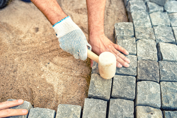 Construction worker installing stone blocks, creating pavement on road, sidewalk or path. - Photo, Image