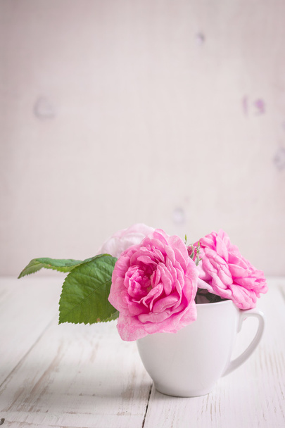 白い木製の背景にピンクの紅茶バラ - 写真・画像