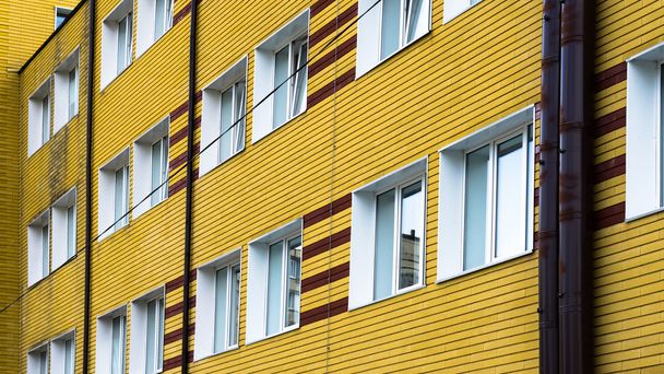 Muitas janelas no edifício de tijolos amarelos
 - Foto, Imagem