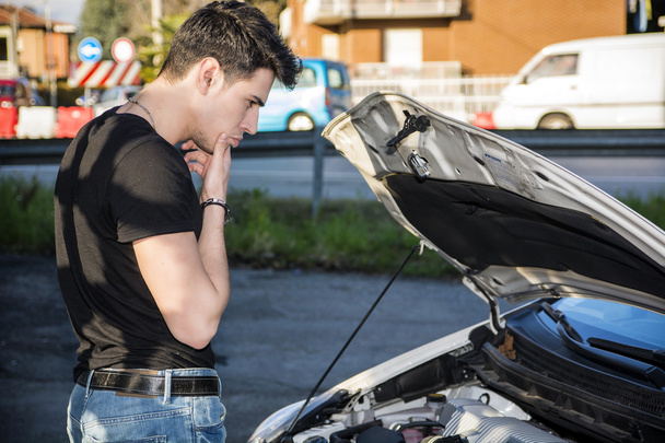 Handsome young man trying to repair a car engine - Photo, Image