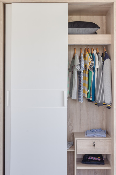 детская одежда висит в белом шкафу
  - Фото, изображение