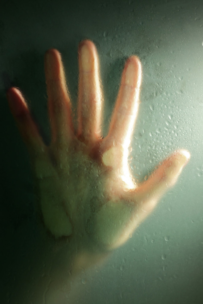 Female hand behind  wet glass, close-up - Foto, Imagem