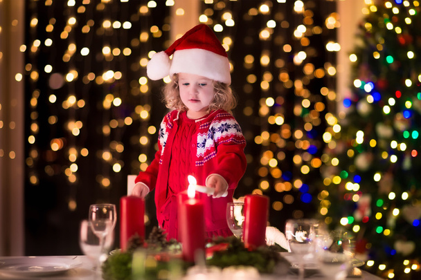 Little girl lighting candles at Christmas dinner - Photo, Image